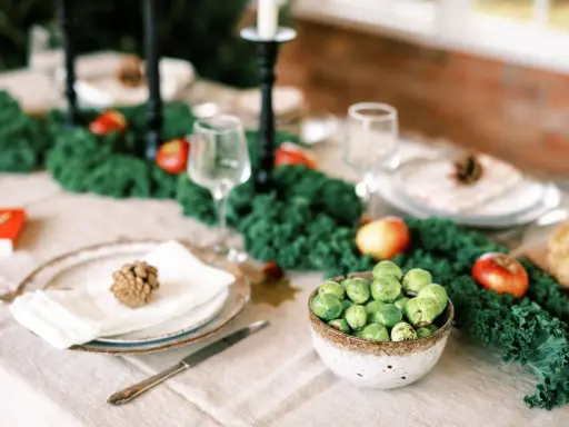 Vacker juldukning inspiration med grönt kale, äpplen och rosenkål. En rustik dukning som bjuder in till fest.