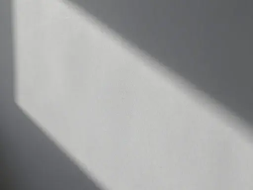 Światło podkreśla nierówności na elewacji, tworząc cień o geometrycznym kształcie.