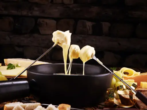 Fondue au fromage, une des spécialités culinaires parisiennes, servie avec du pain et des raisins.