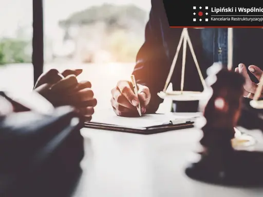 Prawnik podpisuje dokumenty, symbol sprawiedliwości i młotek sędziowski sugerują postępowanie egzekucyjne.