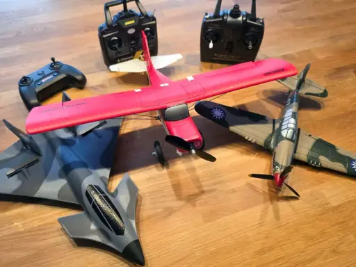 Mehrere ferngesteuerte Flugzeuge, darunter ein rotes Kunstflugmodell und ein Tarnkappenbomber, liegen bereit, um abzuheben.