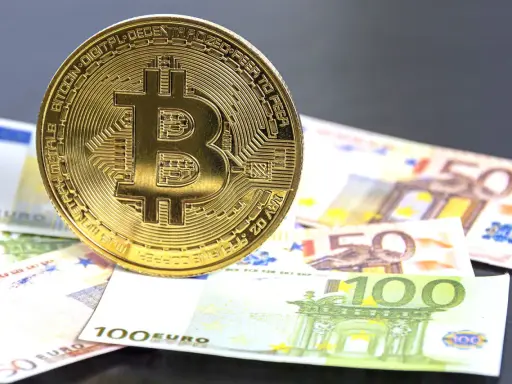 Moneda de Bitcoin sobre billetes de euro. El futuro del euro digital podría ser así.