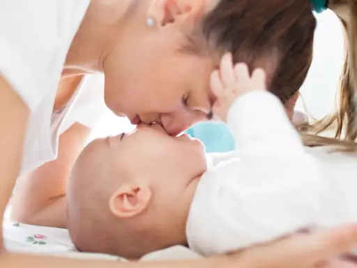 Czuły pocałunek mamy dla jej 3 miesięcznego dziecka.