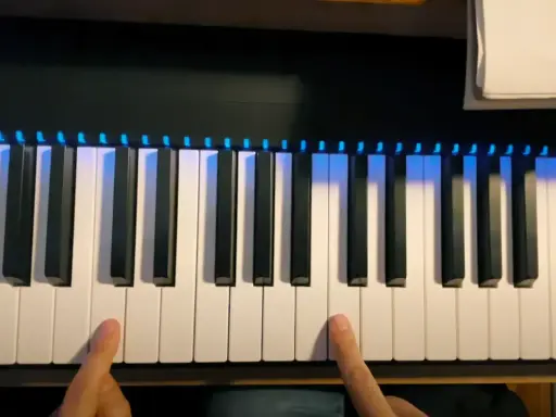 Deux doigts prêts à jouer un accord sur un piano numérique avec des lumières bleues illuminant les touches.