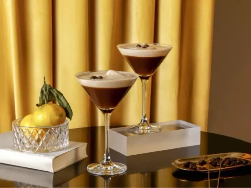 Zwei elegante Gläser mit cremigem Espresso-Martini-Look, garniert mit Kaffeebohnen. Ein alkoholfreier Genuss, der Luxus ausstrahlt.