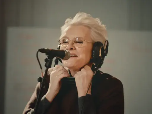 Eva Dahlgren med hörlurar och mikrofon, fångad i ett känslosamt ögonblick under en konsert.