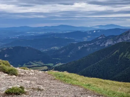 Kamienista ścieżka prowadzi przez zielone zbocza w kierunku malowniczych gór Mała Fatra.