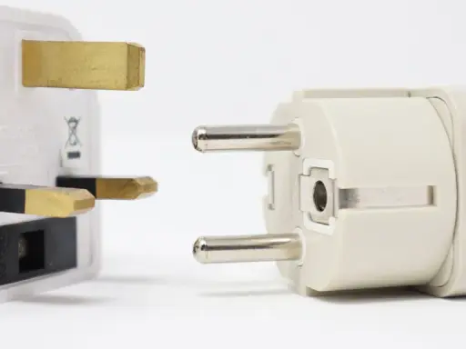 Reiseadapter für den Strom in Spanien. Ein britischer Stecker trifft auf einen europäischen Stecker.