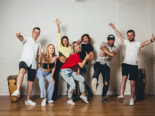 Grupa ludzi wesoło pozuje, gotowa do tańca zouk.