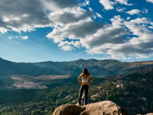 Wanderin auf einem Felsvorsprung mit Blick auf die Berge, ein perfekter tagesausflug madrid.