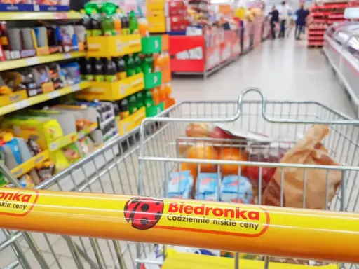 Wózek sklepowy z zakupami w Biedronce, widok z perspektywy klienta.