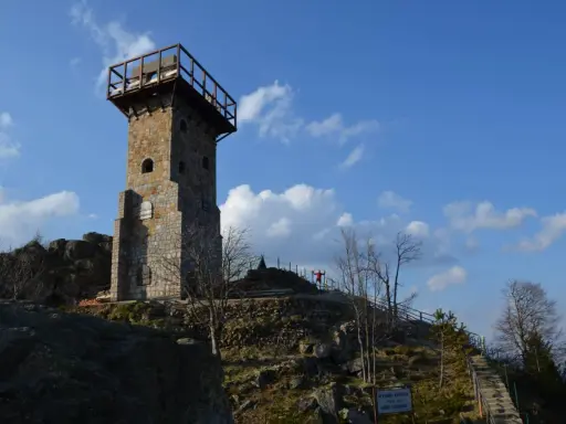 Wysoki kamień, wieża widokowa na szczycie góry, z drewnianym tarasem i schodami prowadzącymi do niej.