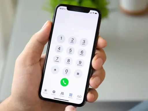 Dłoń trzyma smartfon z klawiaturą numeryczną. Chcesz wiedzieć, jak sprawdzić numer? Wpisz go na klawiaturze telefonu.