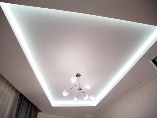 Nowoczesny sufit napinany lustrzany z podświetleniem LED i designerską lampą.
