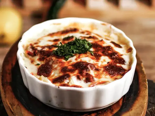 En krämig lasagne vegetarisk med gyllene ost och färska örter, serverad i en vit ugnsform.