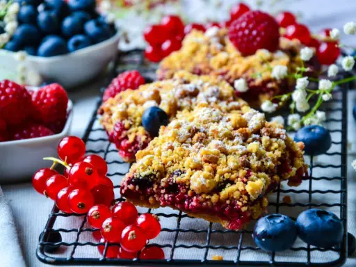 Délicieux crumble aux fruits rouges, garni de framboises, myrtilles et groseilles, saupoudré de sucre glace.