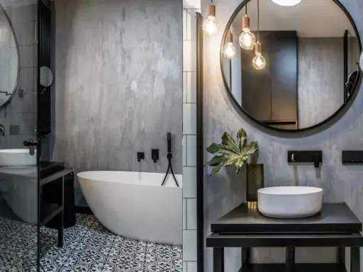 Nowoczesna łazienka w stylu loft z wolnostojącą wanną, umywalką nablatową i betonową ścianą.