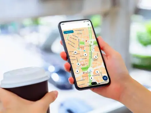 Persona usa un app cargadores eléctricos en su móvil para encontrar puntos de recarga en un mapa.