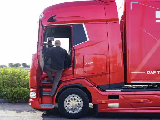 Hombre subiendo a un camión rojo DAF XG Plus.