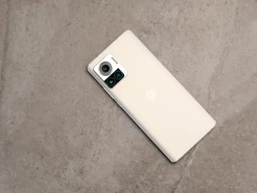 Jasny telefon Motorola edge 30 ultra z potrójnym aparatem na szarym, kamiennym tle.
