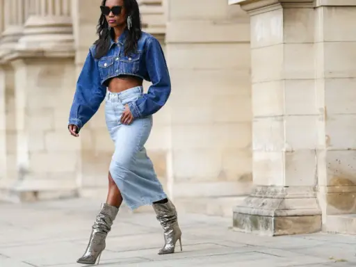 Modella con giacca di jeans corta e gonna lunga, stivali argento scintillanti. Un look che ricorda la moda degli anni '80.