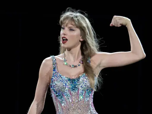 Taylor Swift flexar armen i en glittrig outfit. Undrar du hur mycket kostar Taylor Swift biljetter?