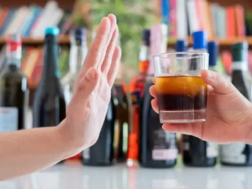 Dłoń odrzuca szklankę z alkoholem, symbolizując początek leczenia alkoholizmu.