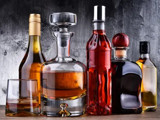 Karafka z koniakiem i inne butelki z brandy na drewnianym blacie.