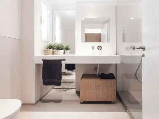 Baño moderno con lavabo flotante, mueble de madera y plantas. Ideal para quienes buscan reformar baño precio.