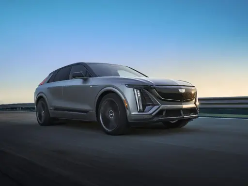 Cadillac Lyriq, un SUV eléctrico que representa el futuro de las marcas americanas de coches, avanza por una carretera al atardecer.