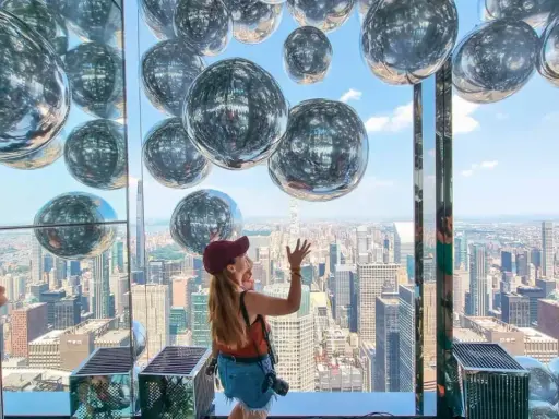 Kobieta cieszy się widokiem z Summit One Vanderbilt, otoczona lśniącymi kulami.