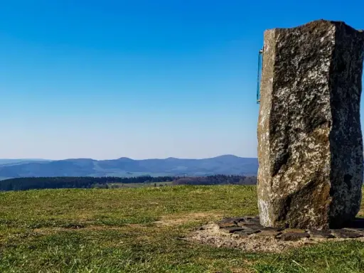 Steinerner Gedenkstein auf der Wasserkuppe mit Blick über Hügel und Täler.