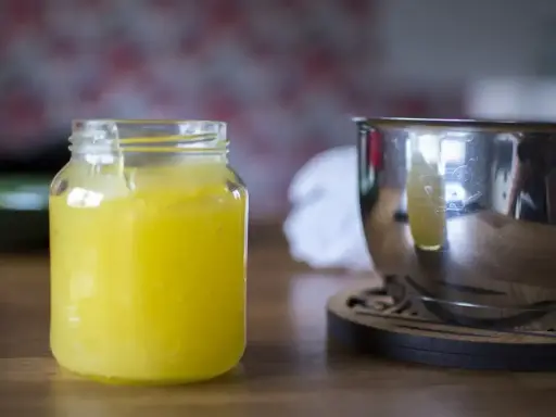 En burk med hemgjord lemon curd står bredvid en metallskål.