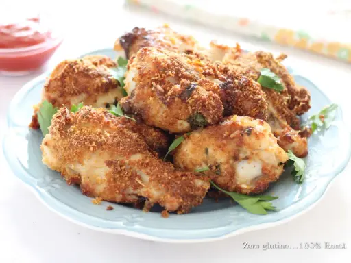 Alette di pollo croccanti in friggitrice ad aria, servite su un piatto azzurro con prezzemolo fresco e una ciotolina di ketchup.