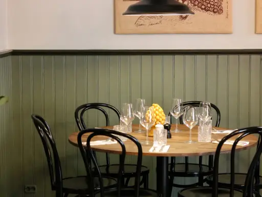 Ett runt bord med dukning för middag, med vinglas och en gul dekoration. En inbjudande atmosfär på la bottega del gusto.