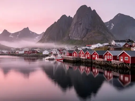 Drömmen om att **bila till Lofoten** blir verklighet vid denna pittoreska hamn med röda fiskebodar och majestätiska berg.