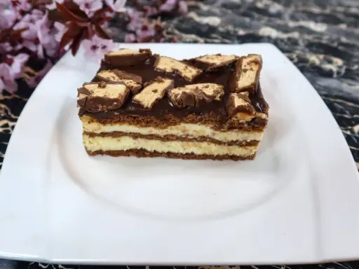 Sernik Milky Way z warstwami kremu i czekolady, ozdobiony kawałkami batoników.