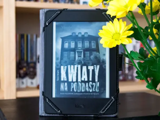Elektroniczna książka z okładką "Kwiaty na poddaszu" obok bukietu żółtych chryzantem.