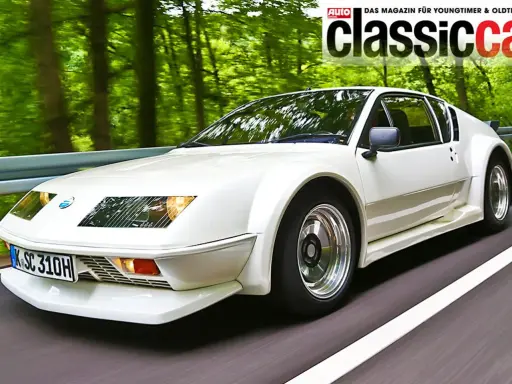 Weißer Renault Alpine A310 fährt auf einer Straße durch einen grünen Wald.
