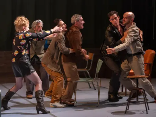 Scène de théâtre tendue. Des hommes se disputent, leurs gestes évoquent une lutte. La scène rappelle la conjugaison du verbe "aboyer" dans un moment de tension.
