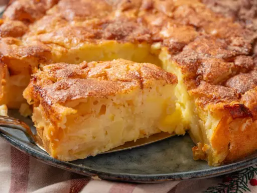 Ein goldbrauner Apfelkuchen mit Zimtstreuseln, der Lust auf tolle Apfelkuchen Rezepte macht. Ein Stück wird gerade herausgehoben.