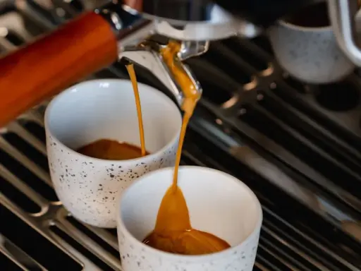 Frisch gebrühter Espresso fließt in zwei Tassen. Hoffentlich schmeckt er nicht zu sauer.