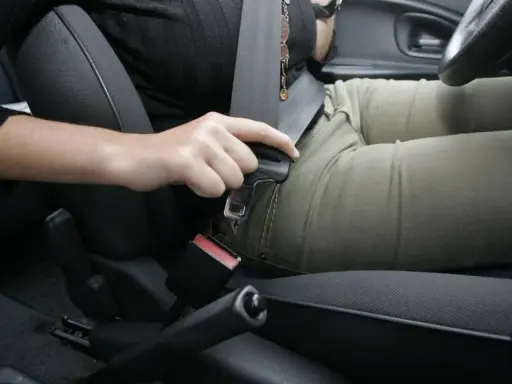 Persona abrochando el cinturón de seguridad. Recuerda, el cinturón de seguridad debe ir siempre abrochado para tu protección.