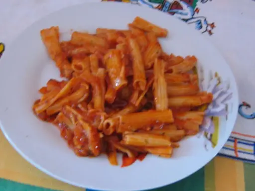 Penne rigate w bogatym sosie pomidorowym, podane na białym talerzu. Pyszny obiad gotowy!
