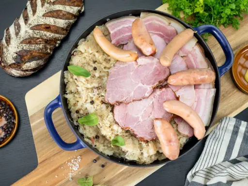 Un plat généreux de choucroute de Noël, garni de saucisses, jambon et lard, accompagné d'une miche de pain rustique.