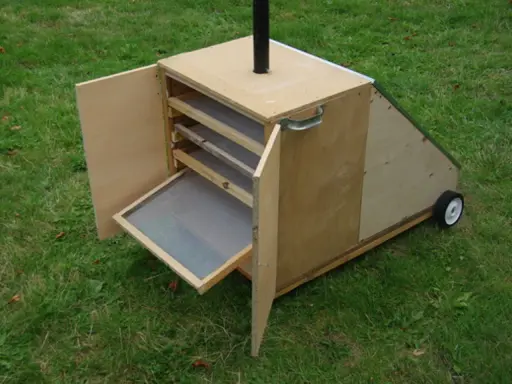 Un sechoir solaire diy en bois, avec des étagères et une porte ouverte sur un tamis. Idéal pour sécher des herbes ou des fruits au soleil.