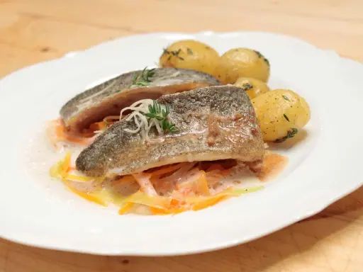 Zartes Forellenfilet braten, serviert mit kleinen Kartoffeln und julieniertem Gemüse in einer leichten Sauce. Ein Genuss!