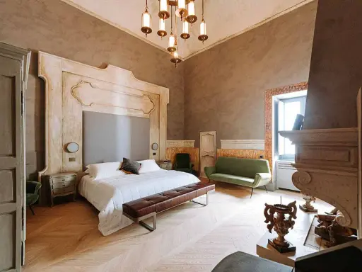 Ett lyxigt sovrum med en stor säng, grön soffa och en imponerande eldstad. Perfekt hotell inredning inspiration för ett elegant hem.