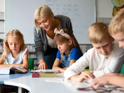 Nauczycielka, jak dobry oligofrenopedagog, wspiera dzieci w nauce przy stolikach.