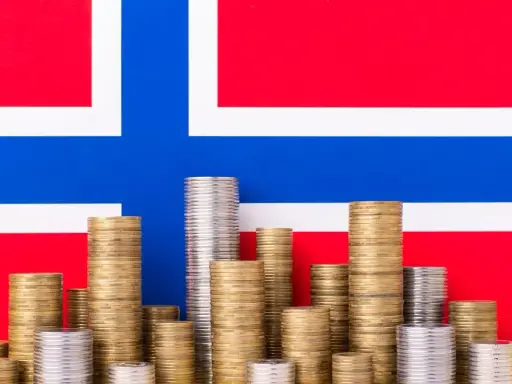 Stosy monet na tle flagi Norwegii symbolizują oszczędności i przyszłość, być może związane z wiekiem emerytalnym w Norwegii.